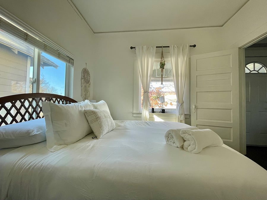 A cozy queen sized bed with fresh linens. Relax and enjoy the large windows and clean aesthetic.