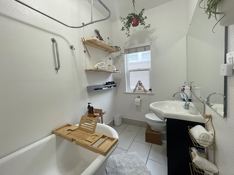 A pristine bathroom equipped with all the amenities, shelving and a classic clawfoot tub/shower combo