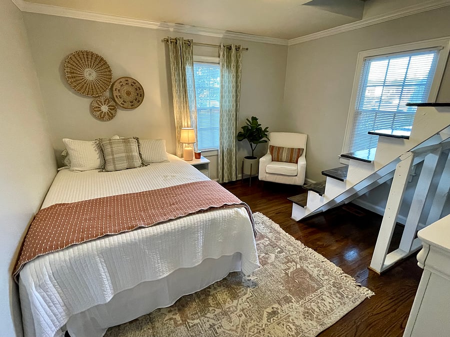 Guest bedroom with queen bed and stairs to upstairs loft