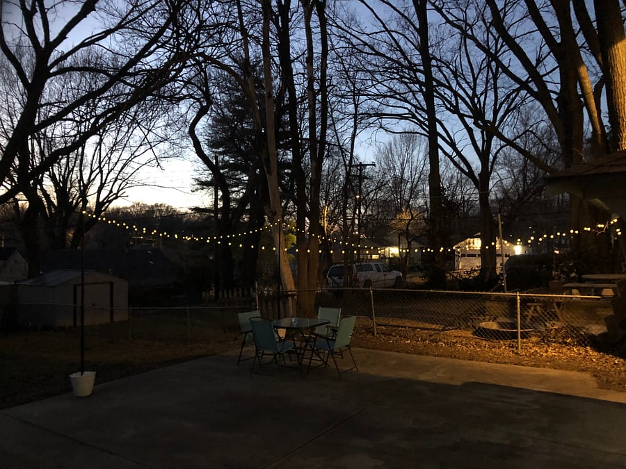 Fully fenced-in yard with outdoor seating and string lights.