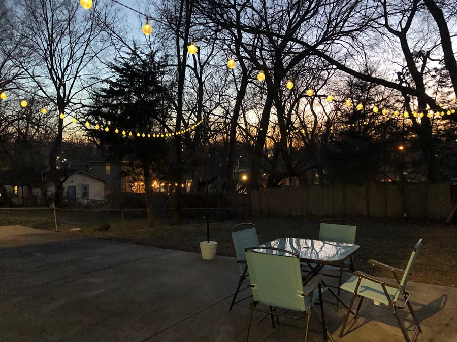 Fully fenced-in yard with outdoor seating and string lights.