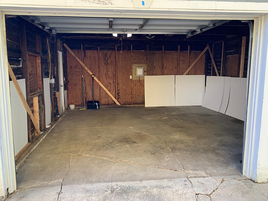 A garage interior spacious enough to accommodate a vehicle, along with additional storage or a motorbike