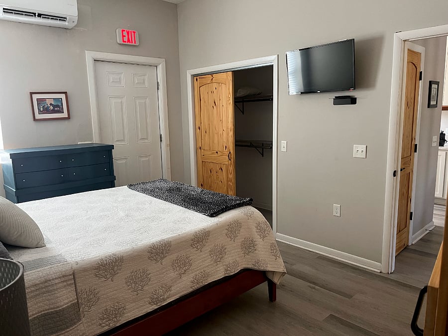 Bedroom with Queen size bed, full closet, dresser Smart TV and ceiling fan.  Door exits to fenced in yard.