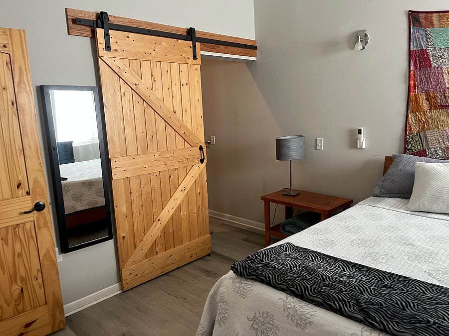 Barndoor separates bedroom from bathroom .