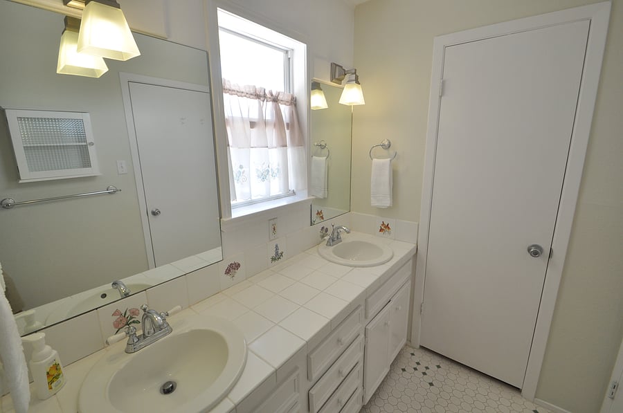 Main full bath has dual sinks, tub shower combo and a view of the front area.