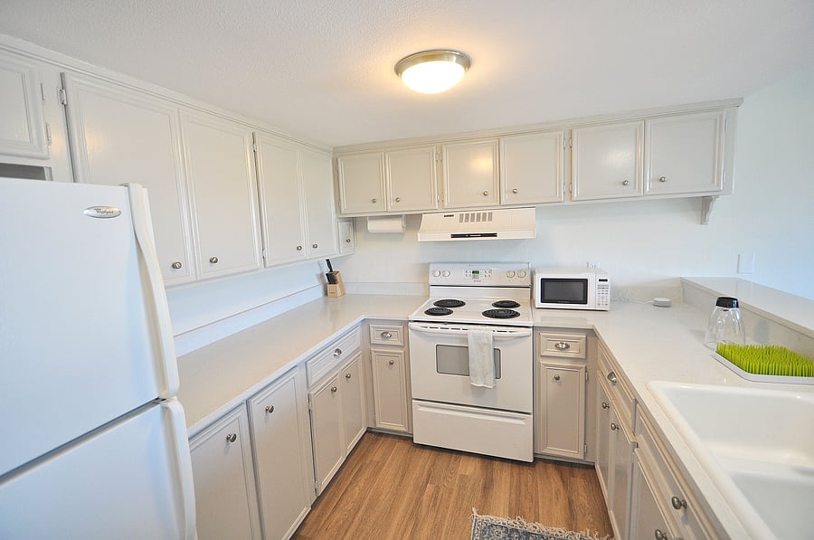 Kitchen has corian counters, light gray cabinets.