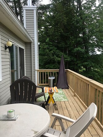 back deck with adirondack chairs, weber propane grill, table with umbrella with four chairs