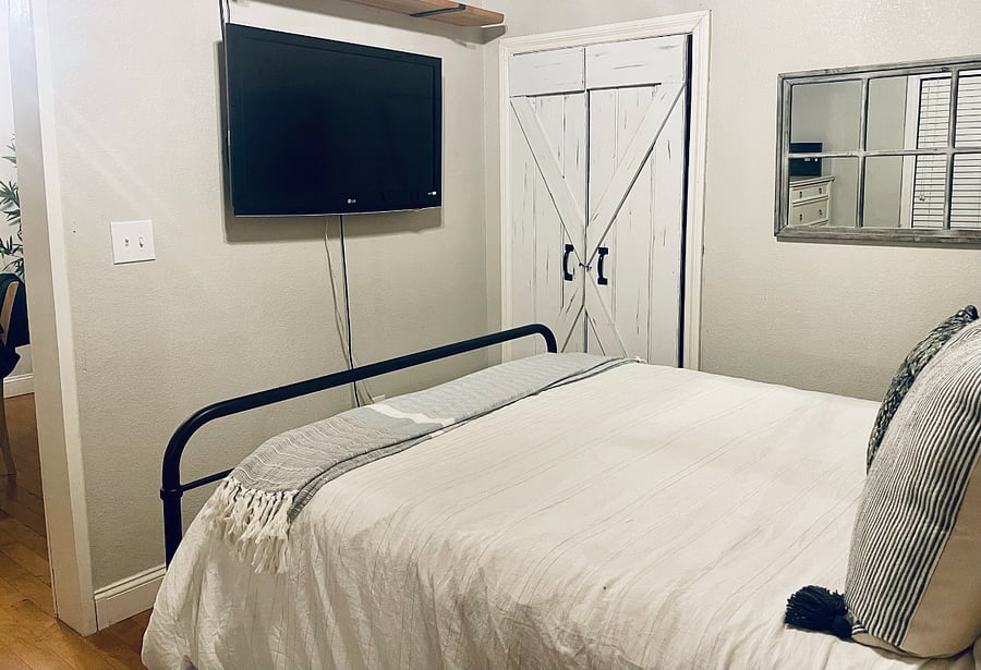 Main Bedroom: Tucked behind a beautiful rustic barn door, enjoy a cozy Queen sized bed, dresser, full length mirror, TV and closet space for hanging clothes.