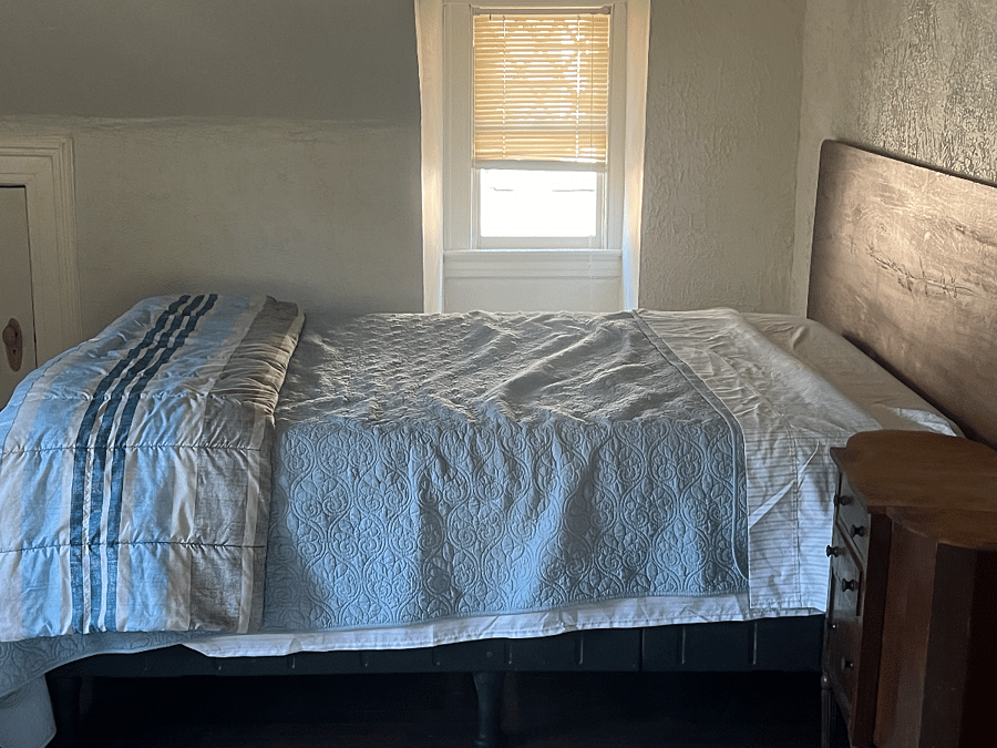 Largest room with queen bed, sitting area, and work desk.
