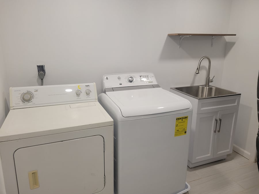 Nice laundry in basement with a new wash sink, new dryer unit and clothes hanging rack.