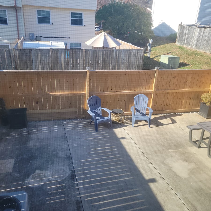 Big fenced patio with picnic table and lounge chairs.