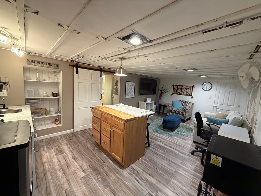 Large smart TV, comfortable living room area, kitchenette with all kitchen amenities. Sliding barn door separates the bedroom area.