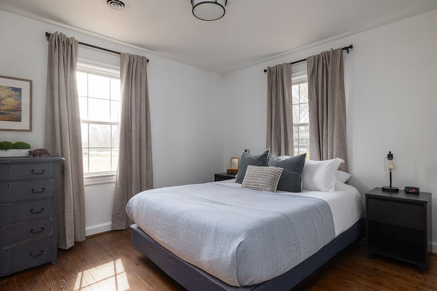 Secondary bedroom with cozy queen bed, dresser, and closet