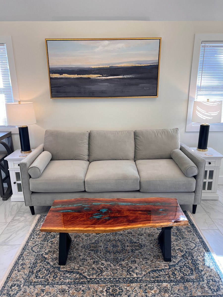 New comfortable sofa with large painting, rug and coffee table that mesh well.
