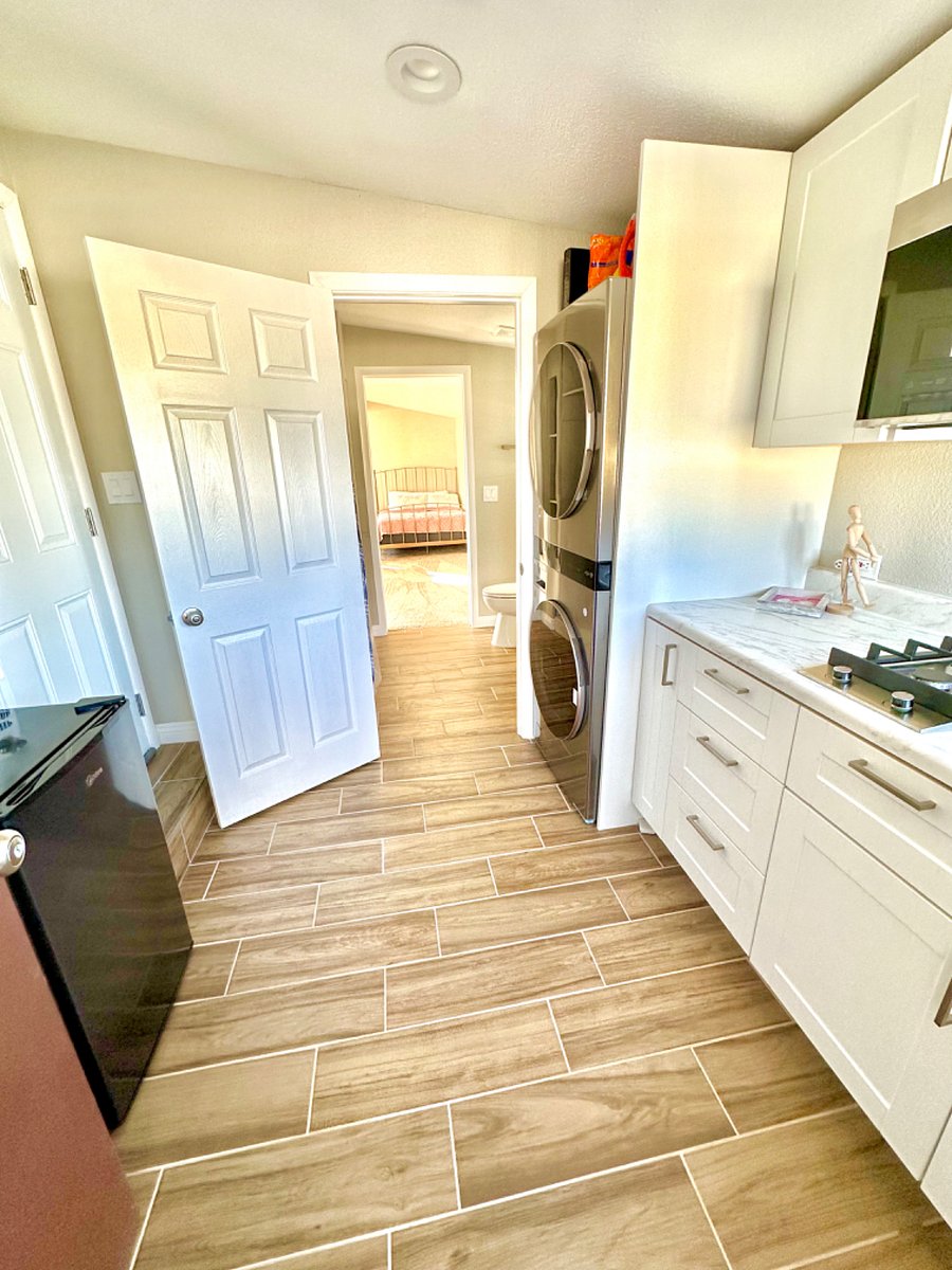 Kitchen and 2 fridges with washer and dryer placed in the corner of the kitchen.