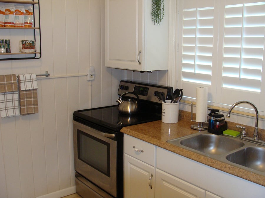 kitchen has new electric stove and aluminum sink with garbage disposal