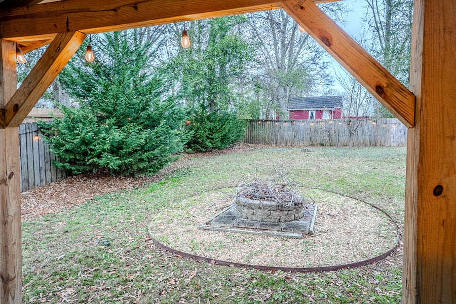 Fenced in backyard with wood fire pit.