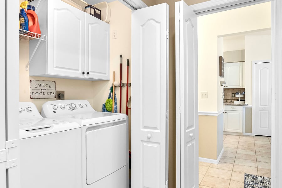 Full-size washer and dryer, iron and ironing board, cleaning tools and essential hardware tools in the cabinet.