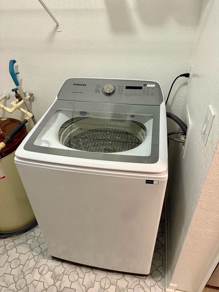 Brand new full-sized Samsung washing machine within the apartment (through the doors to the back of the kitchen).