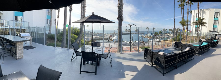 BBQ and lounge area on upper deck of pool area overlooking Redondo Beach Pier & Harbor
