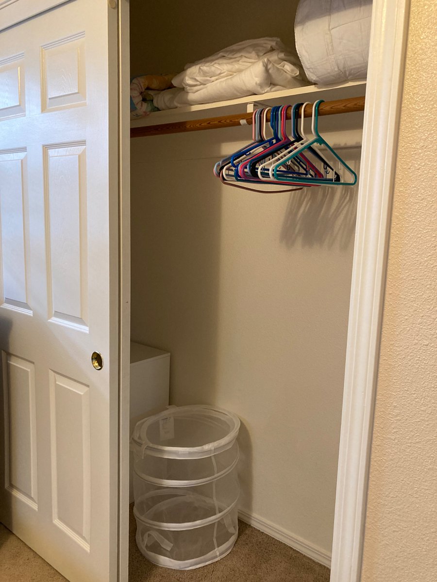 Full-sized bedroom closet with small dresser set, laundry hamper, and lots of space for hanging long and short clothing