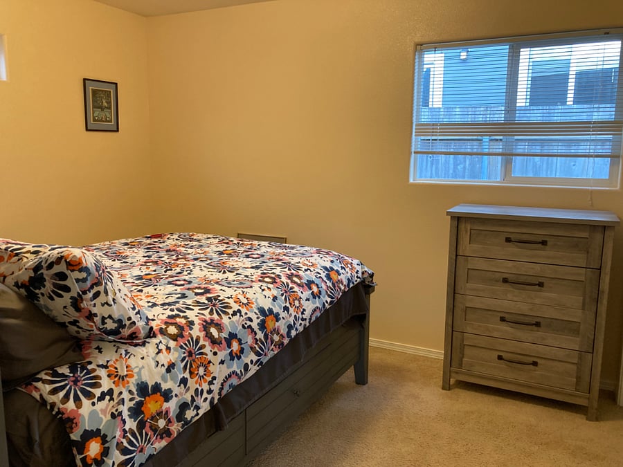 Bedroom has window, dresser, and bedside table. Platform bed has large drawers for storage.
