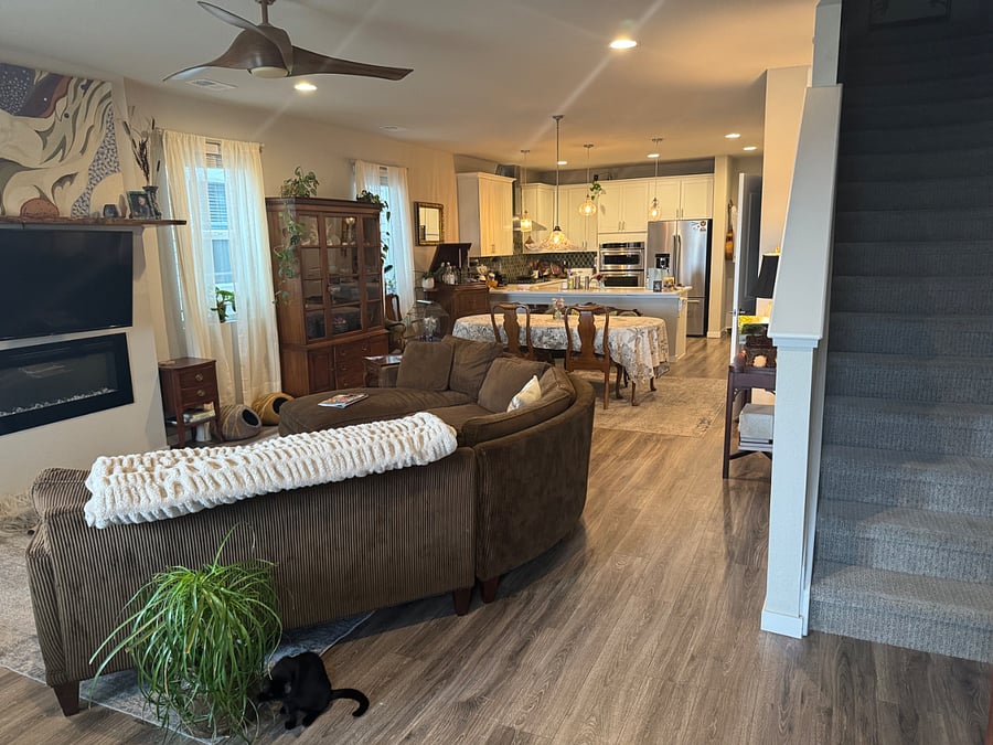 Open floor plan main level with living room, dining area & kitchen viewed from front door entrance. Stairs to upper second level on right.