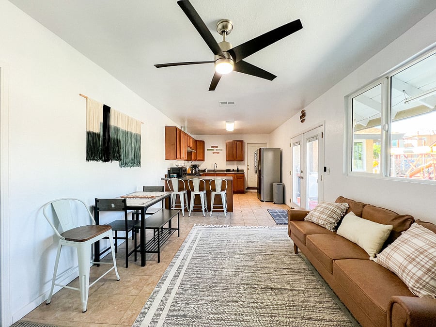 Common living space and kitchen includes 4 barstools, a small dining table and couch. 