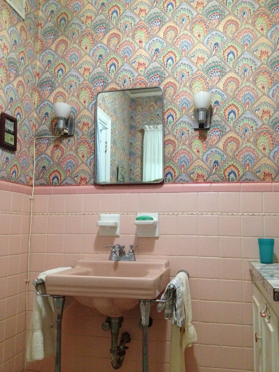 Cheerful bathroom has a tub/shower combo with built in cabinets and laundry holder.