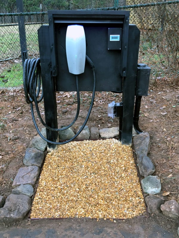 A Tesla charger sits at the end of the asphalt parking lot.