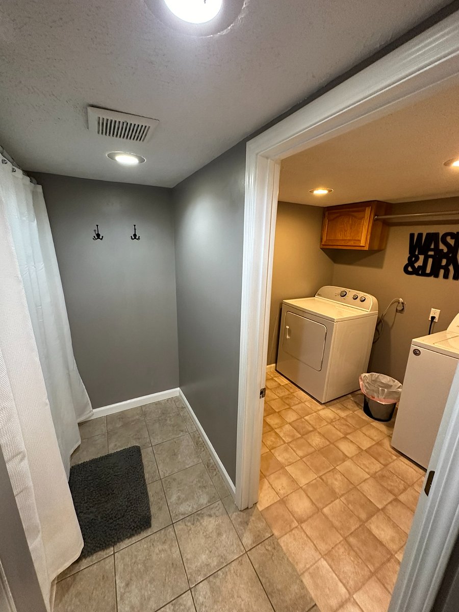 Main-floor bathroom with separate laundry room and hanging rack. 