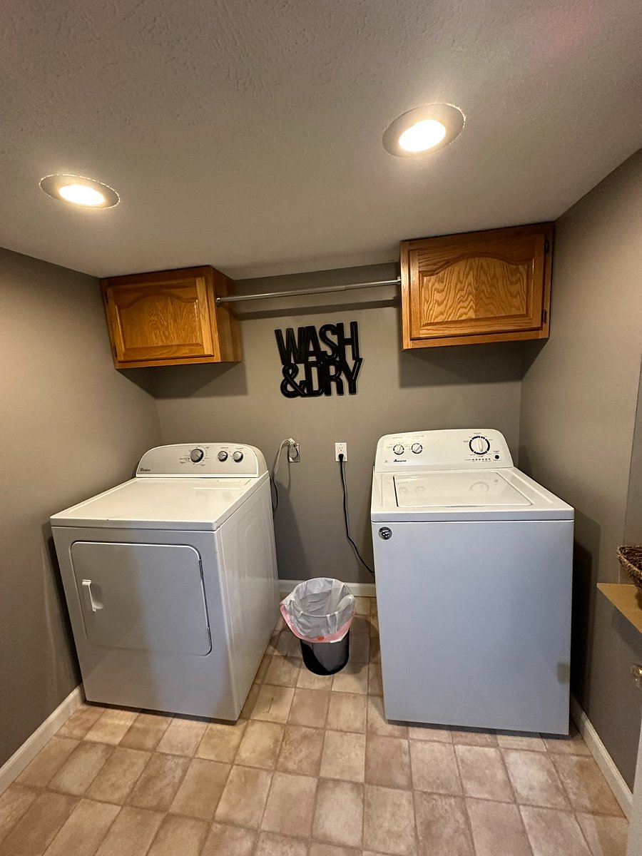 Laundry room with hanging rack and storage cabinets. 