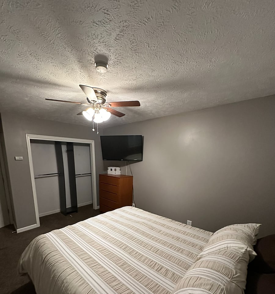 Upstairs master bedroom, open closet, oak dresser, ceiling fan, and 43-inch mounted TV. 