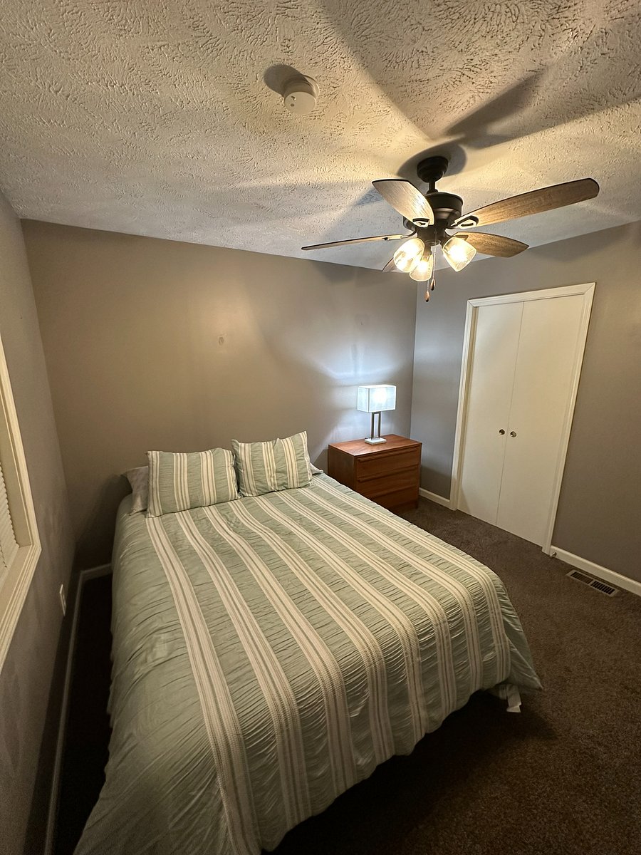 Upstairs bedroom with new ceiling fan, oak dresser, and bedside lamp. 