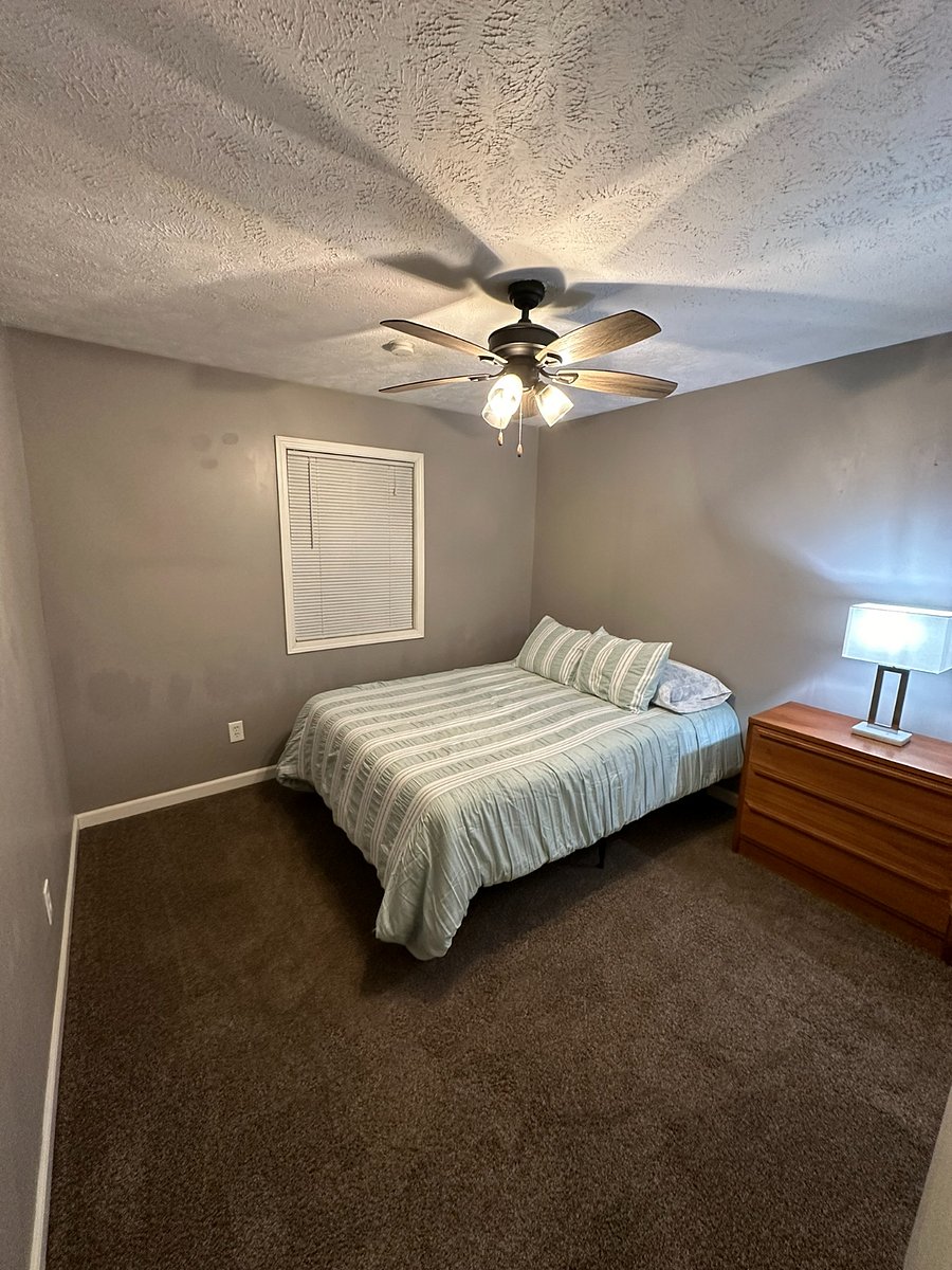 Upstairs bedroom with new ceiling fan, oak dresser, and bedside lamp. 