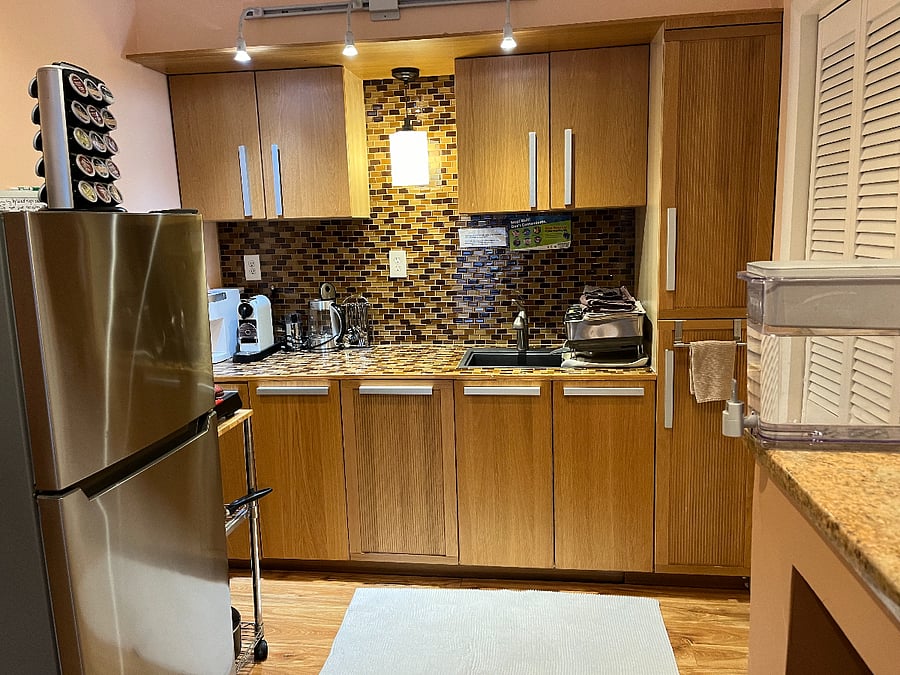 kitchenette with small bar sink. Recycling bin and trash bin under sink.