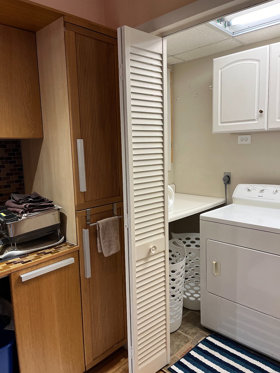 Washer/dryer with storage above the appliances and a folding table to the left available behind folding door to the right of the sink. Fuse box panels in this room.