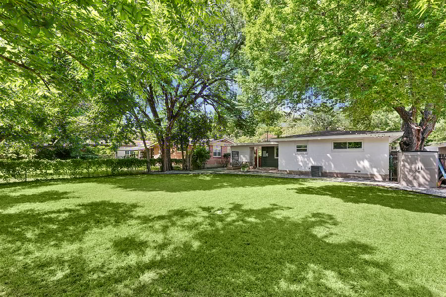 Huge backyard, with plenty of room for pets and activities! Relax on an outdoor sofa, surrounded by clean landscaping, stringed lights, and a canopy of trees!