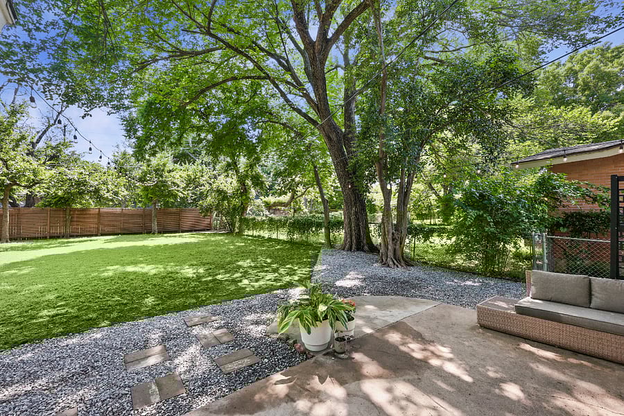 Huge backyard, with plenty of room for pets and activities! Relax on an outdoor sofa, surrounded by clean landscaping, stringed lights, and a canopy of trees!