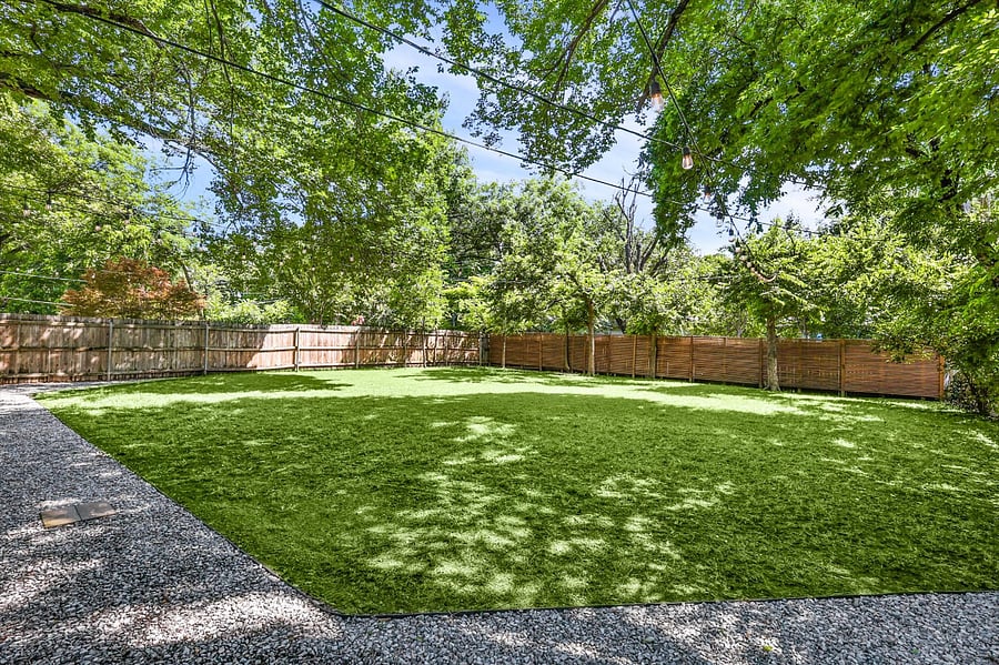 Huge backyard, with plenty of room for pets and activities! Relax on an outdoor sofa, surrounded by clean landscaping, stringed lights, and a canopy of trees!