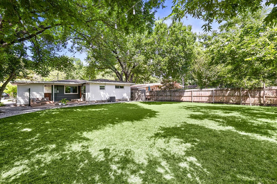 Huge backyard, with plenty of room for pets and activities! Relax on an outdoor sofa, surrounded by clean landscaping, stringed lights, and a canopy of trees!