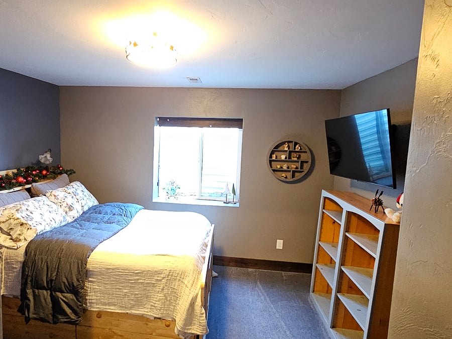Different view of large window with dark shade and space in bedroom.