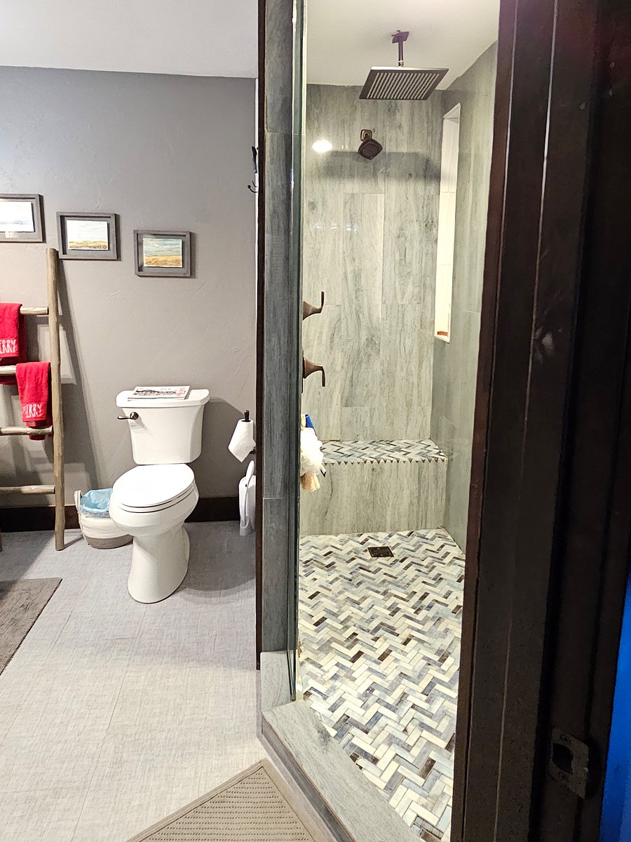 second view of bathroom and spa shower with bluetooth speaker/fan and lights in shower. Floor and shower are all tile. Shower has rainfall and regular shower heads for you to chose your shower experience.
