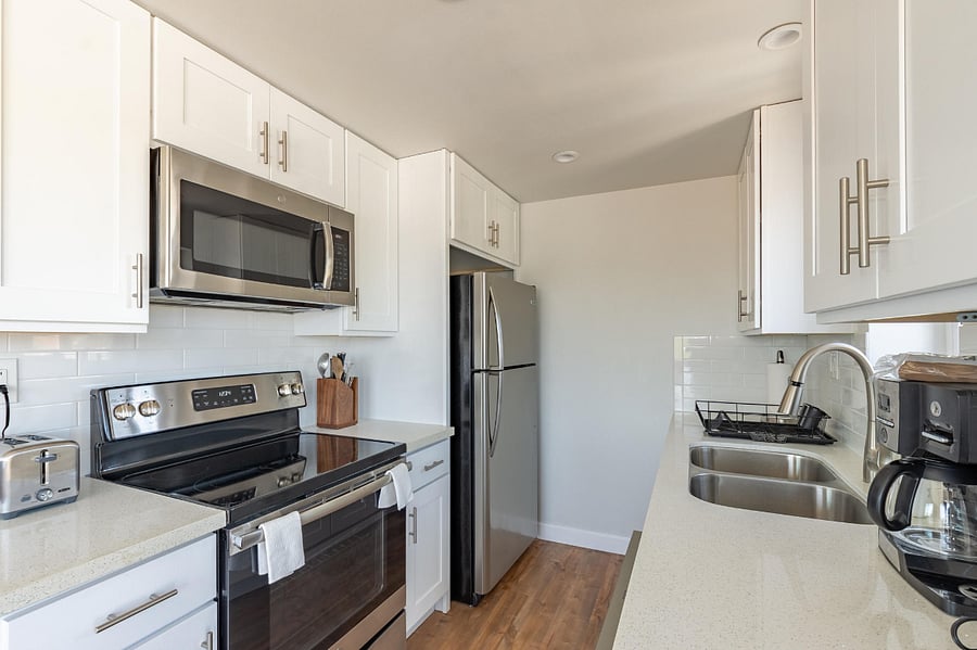 Modern kitchen with stainless steel appliances and quartz countertops.