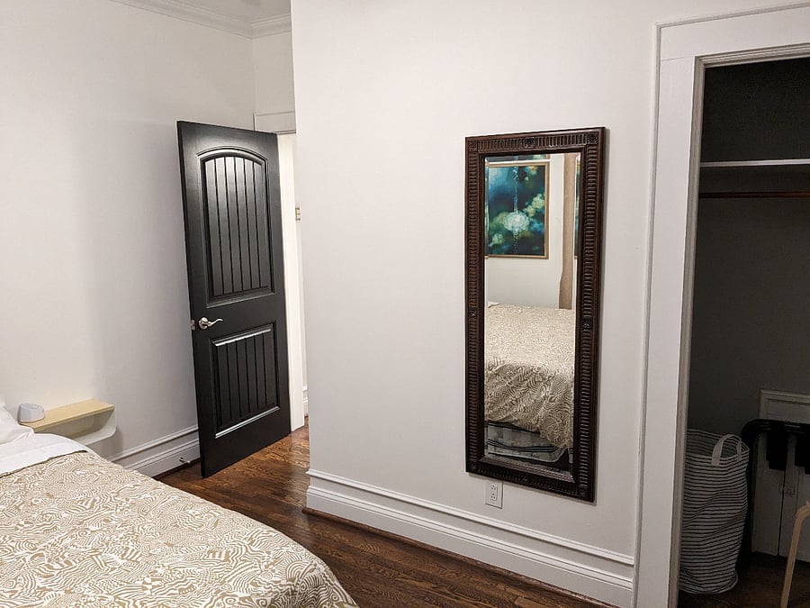 Closet with hangers, luggage racks, and full length mirror.