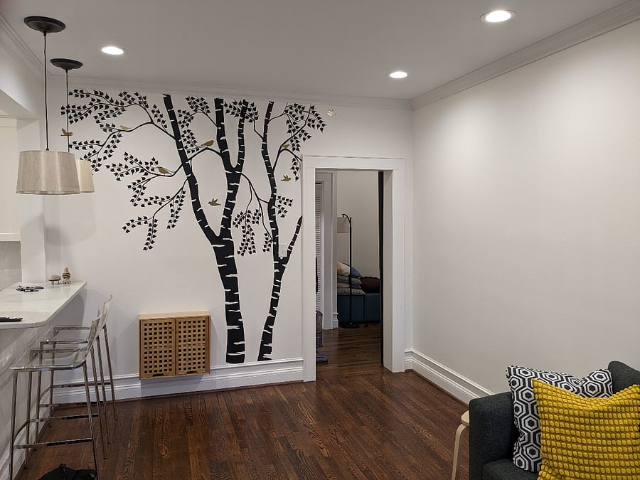 Modern wall art in living room, with two-seat bar counter pass through to kitchen (left) and sliding door to second bedroom/den, half bath, and laundry (right).