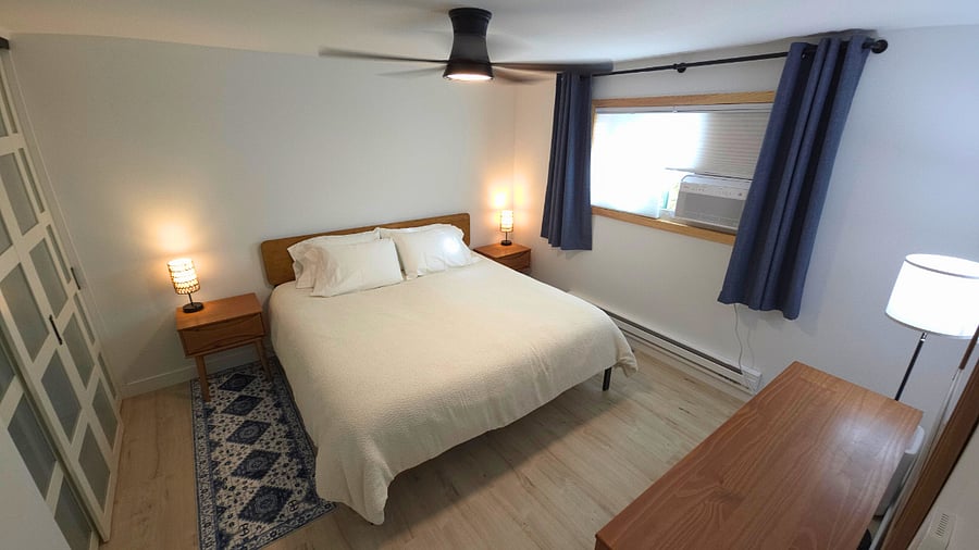 Main bedroom with Sleep Number king bed, 6-drawer dresser, two nightstands with storage, lamps with USB ports, air purifier, blackout curtains, mirror, and walk-in closet with hangers, dirty laundry hamper, and shelves.
