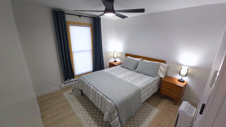 Secondary bedroom with memory foam queen bed, two nightstands with storage, air purifier, blackout curtains, lamps with USB ports, and closet with hangers, laundry hamper, and shelves. Extra blankets and two sets of sheets in storage bins under bed.
