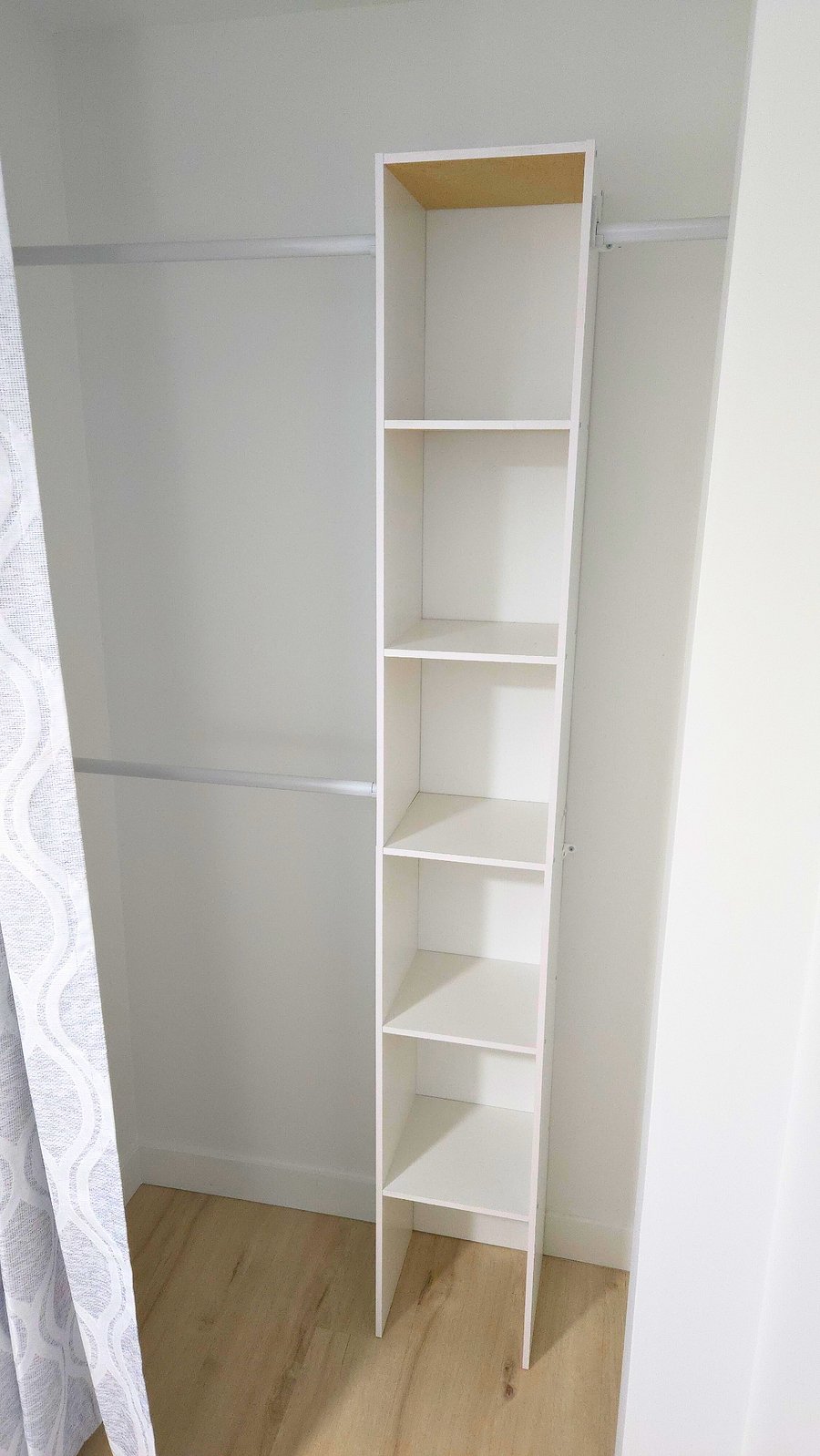 Secondary bedroom closet with hangers, laundry hamper, and shelves.