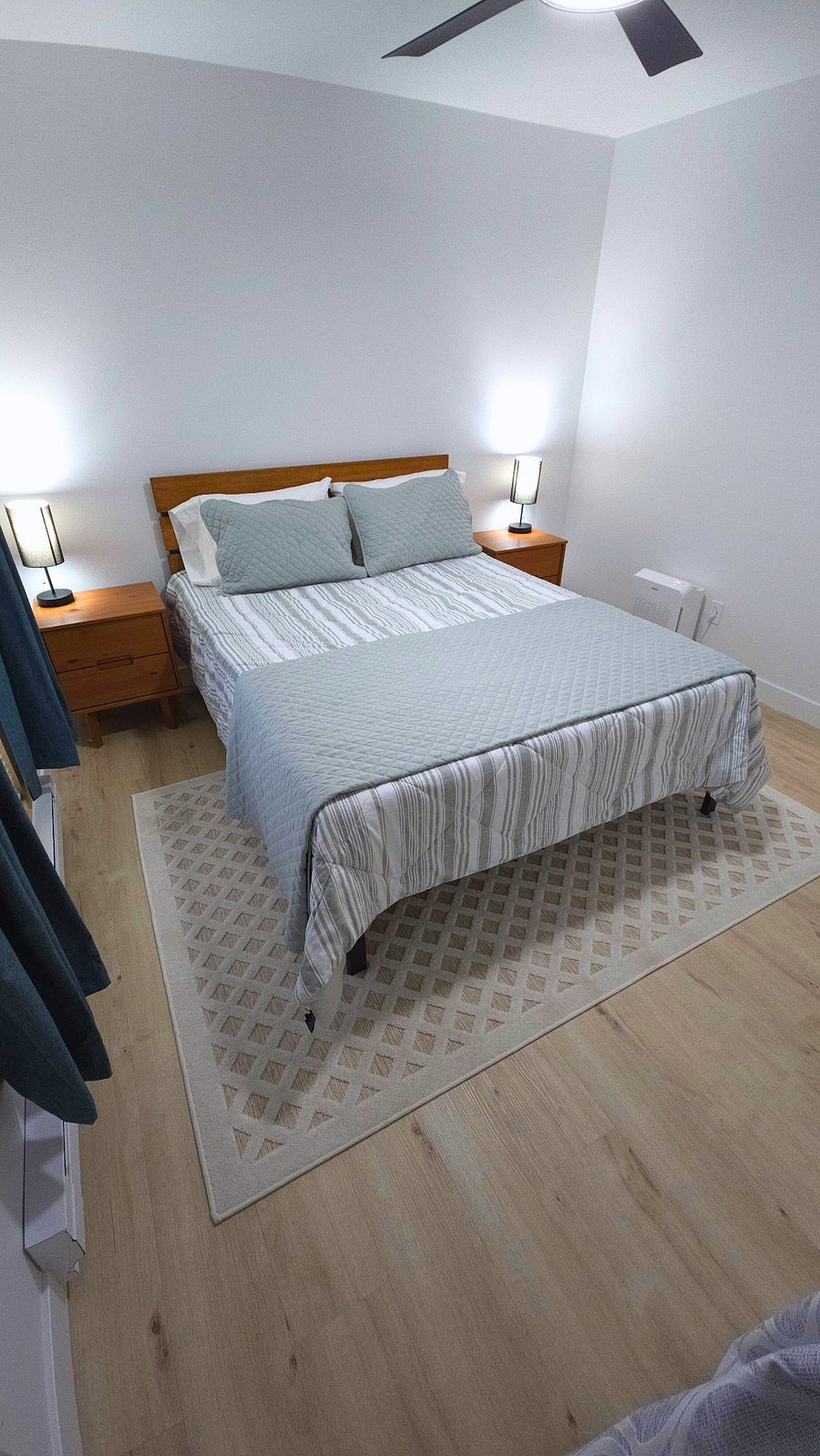 Secondary bedroom with memory foam queen bed, two nightstands with storage, air purifier, blackout curtains, lamps with USB ports, and closet with hangers, laundry hamper, and shelves.